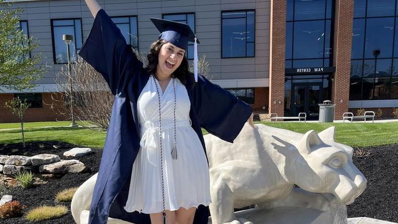 New Penn State graduate Anna Raffeinner celebrates with a joyful expression with the Lion Shrine on the 365英国上市杜波依斯分校 campus, 就在PAW中心外面